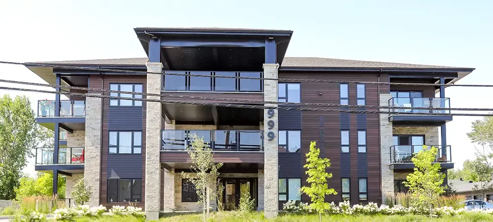 Balcons vitrés et façade moderne avec aménagement paysager fleuri – logements luxueux Ratelle & Ratelle Lanaudière