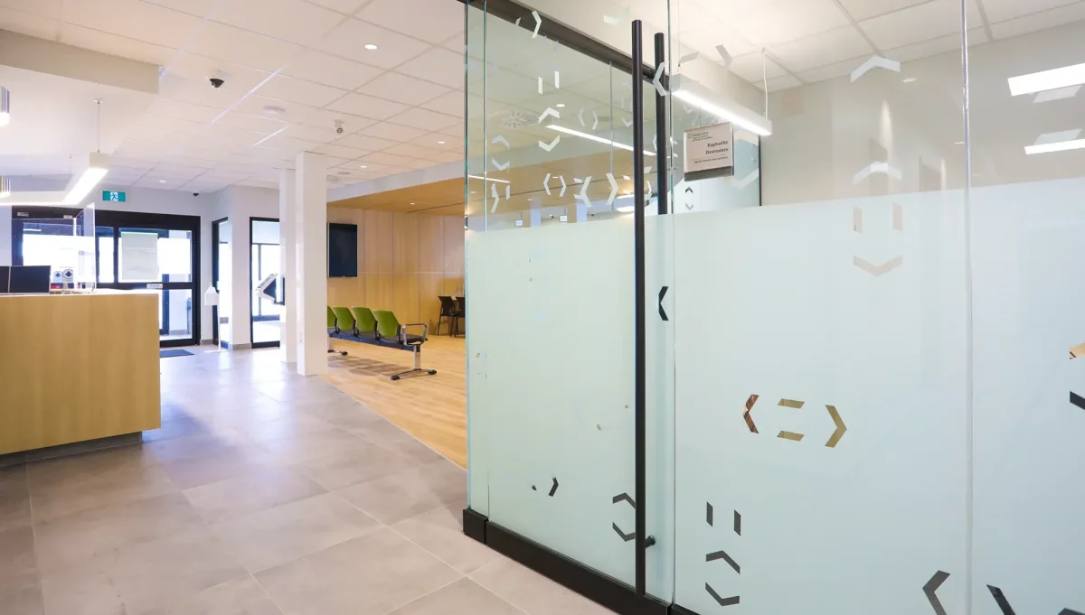 Salles de consultation avec cloisons vitrées givrées et accents de bois – projet institutionnel Desjardins Lanaudière