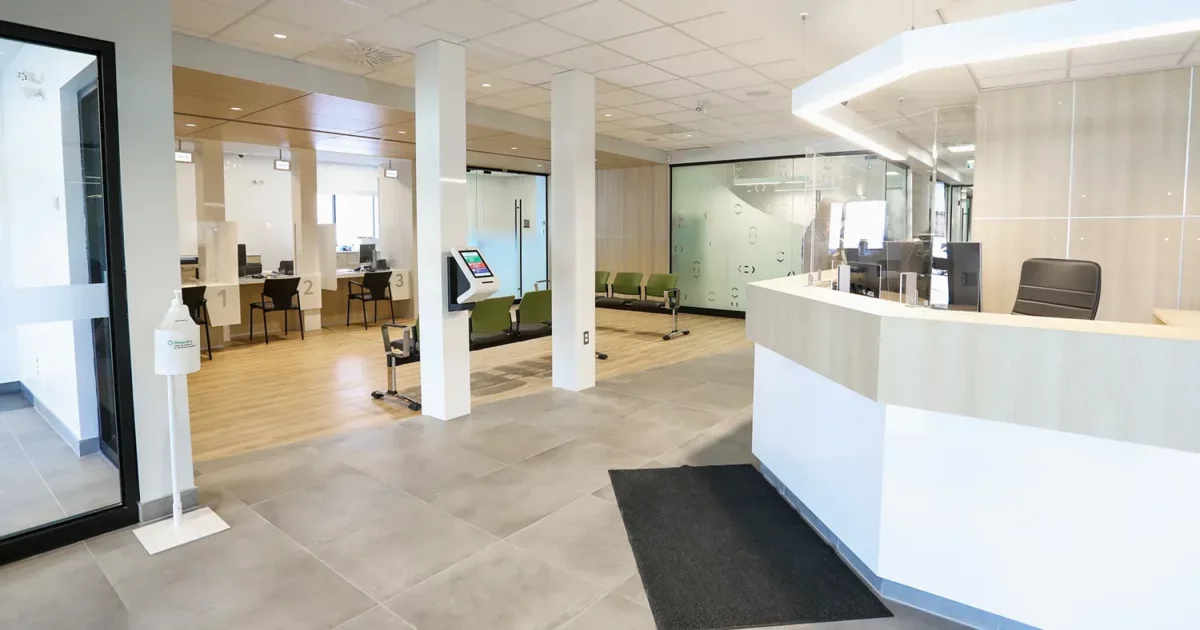 Aire de service avec comptoirs blancs, bornes libre-service et postes de travail – Caisse Desjardins par BGC