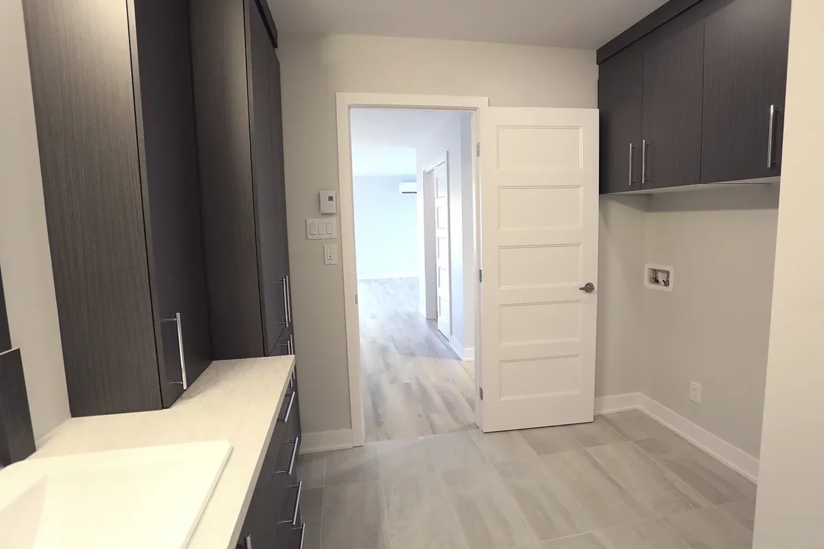 Salle de bain moderne avec douche vitrée, armoires brunes et vanité blanche – projet multi-résidentiel Joliette par BGC