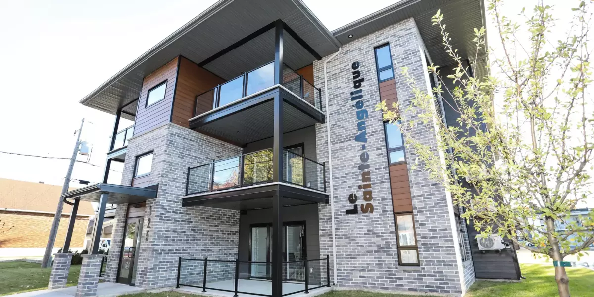 Façade de l'immeuble Le Sainte-Angélique avec brique grise, balcons noirs et accents orange – 12 unités Joliette par BGC