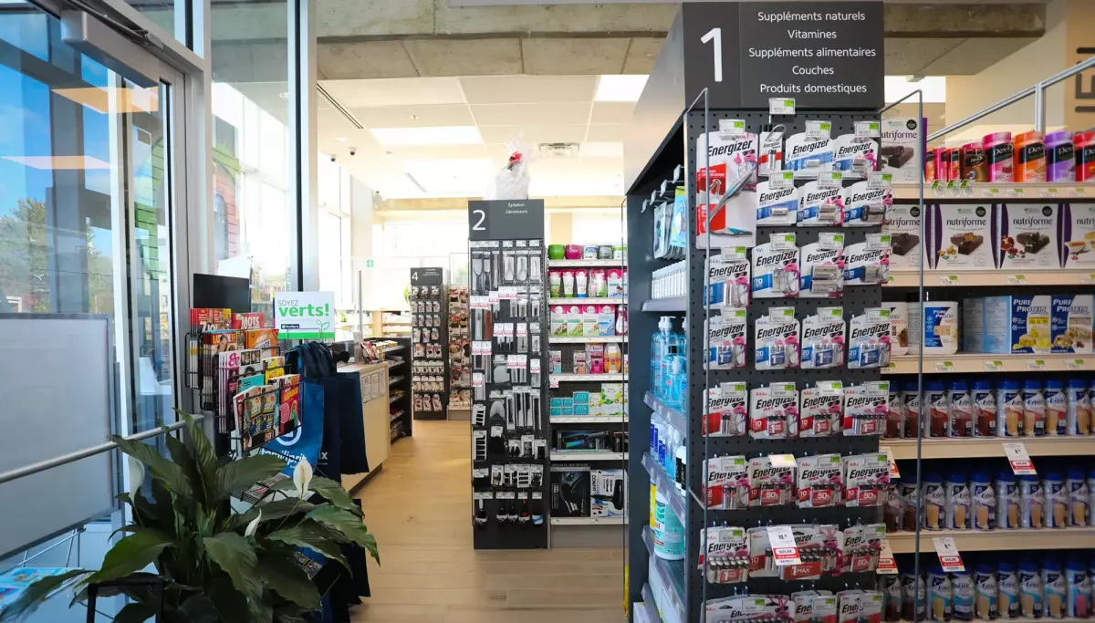 Intérieur lumineux avec vitrine, plantes et étalages de produits – pharmacie Familiprix Joliette par BGC