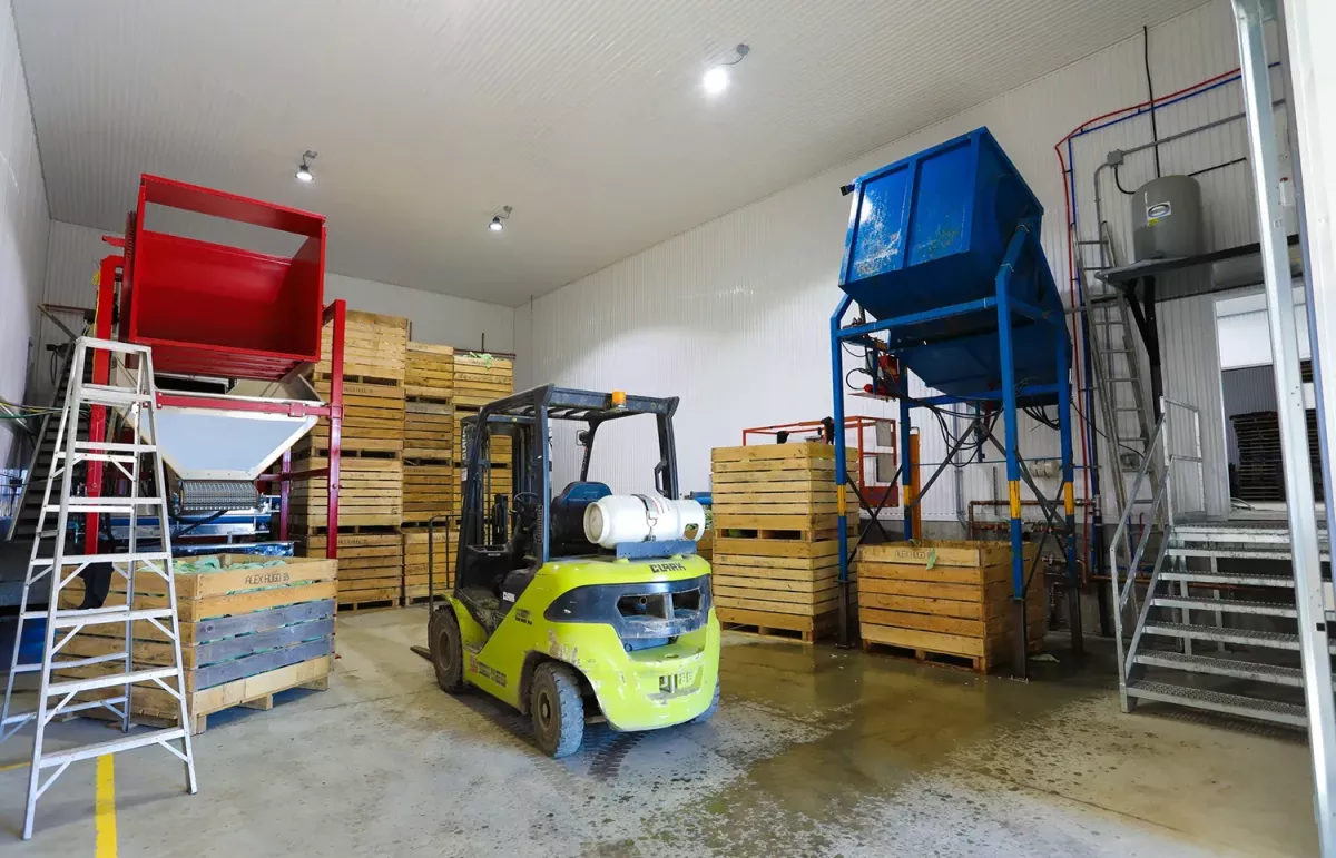Intérieur d'entrepôt avec chariot élévateur et caisses de bois – projet agricole Ferme Jobin & Roberge par BGC