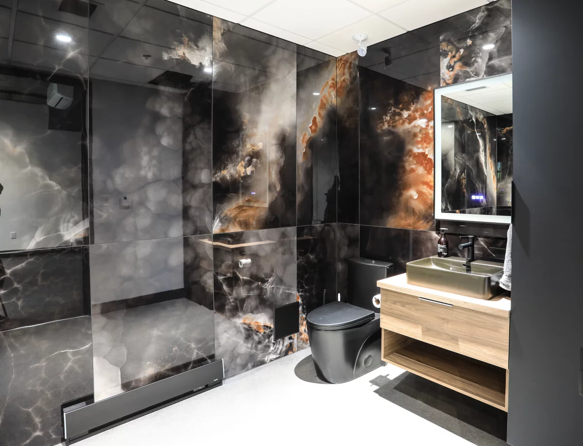 Salle de bain avec panneaux muraux effet nébuleuse, douche vitrée, toilette noire et vanité en bois