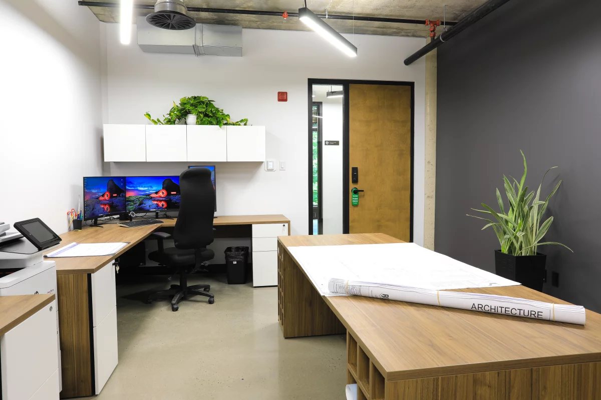 Bureau exécutif avec mobilier noir, plantes tropicales et vue sur la forêt