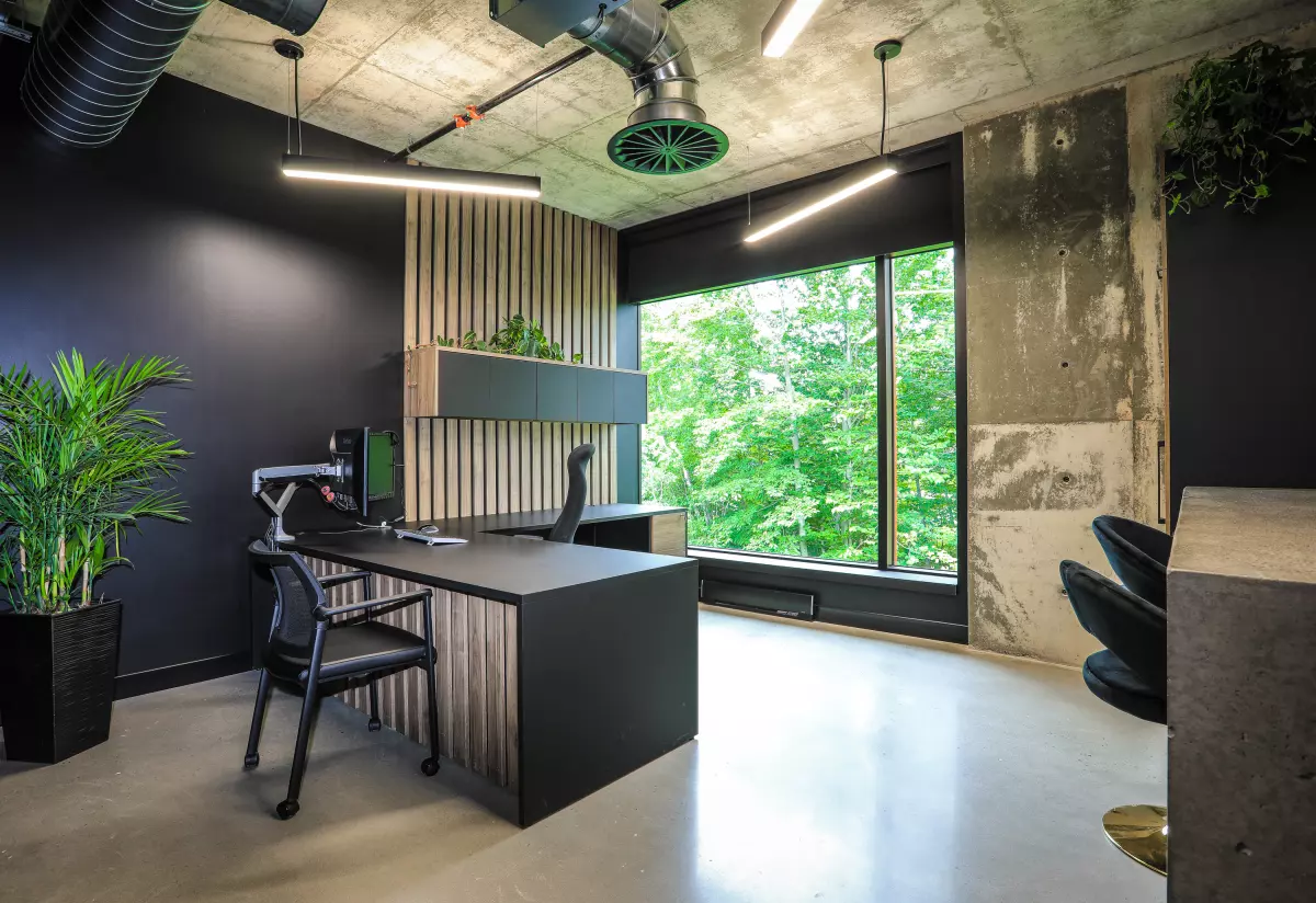 Poste de travail avec bureau en L, murs foncés et grande fenêtre sur la nature