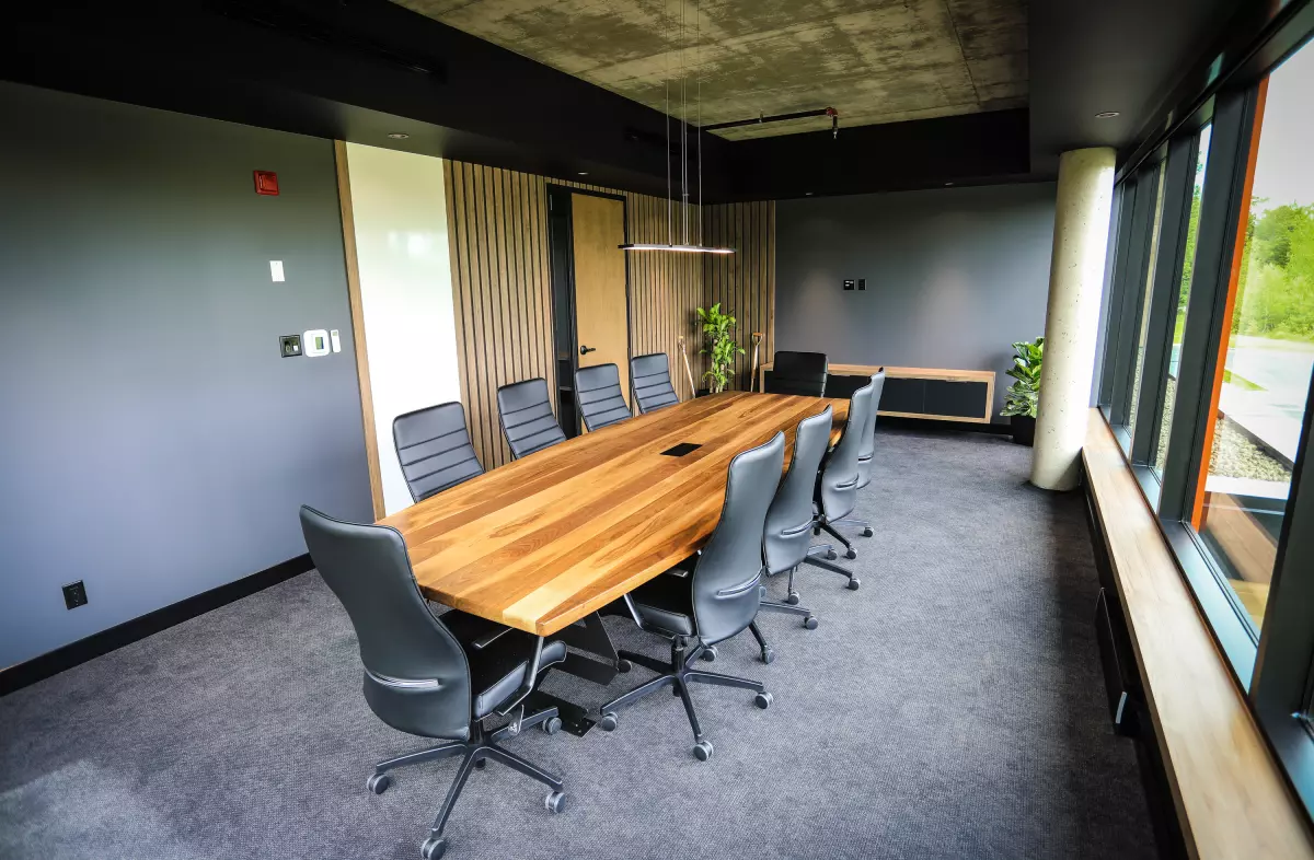 Salle de conférence avec table en bois live-edge, chaises grises et lattes murales