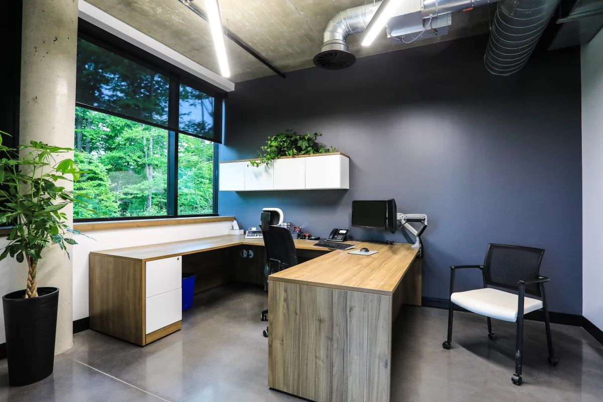 Bureau exécutif avec mobilier noir, plantes tropicales et vue sur la forêt