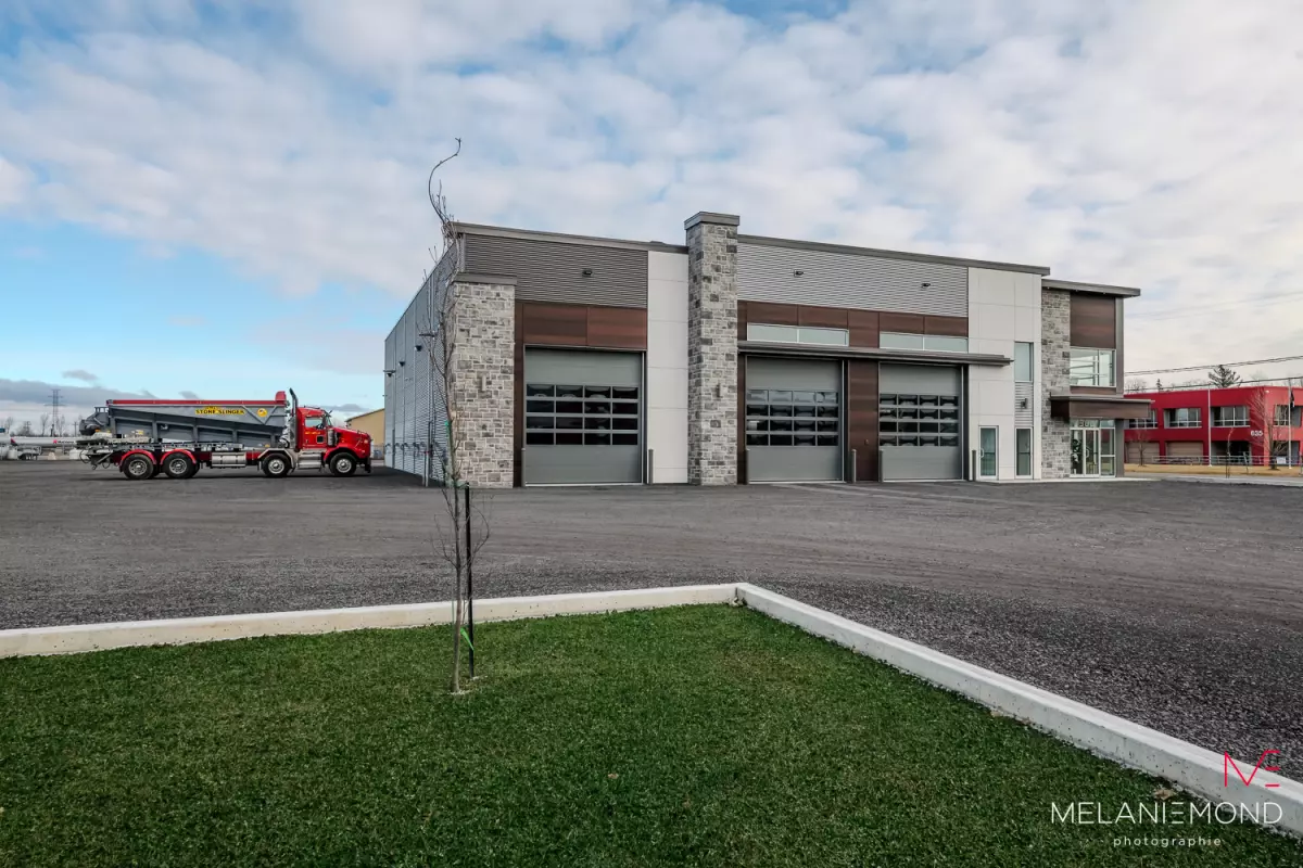 Garage industriel avec trois portes de service et camion rouge – bâtiment d'acier Épandage YFL Joliette par BGC