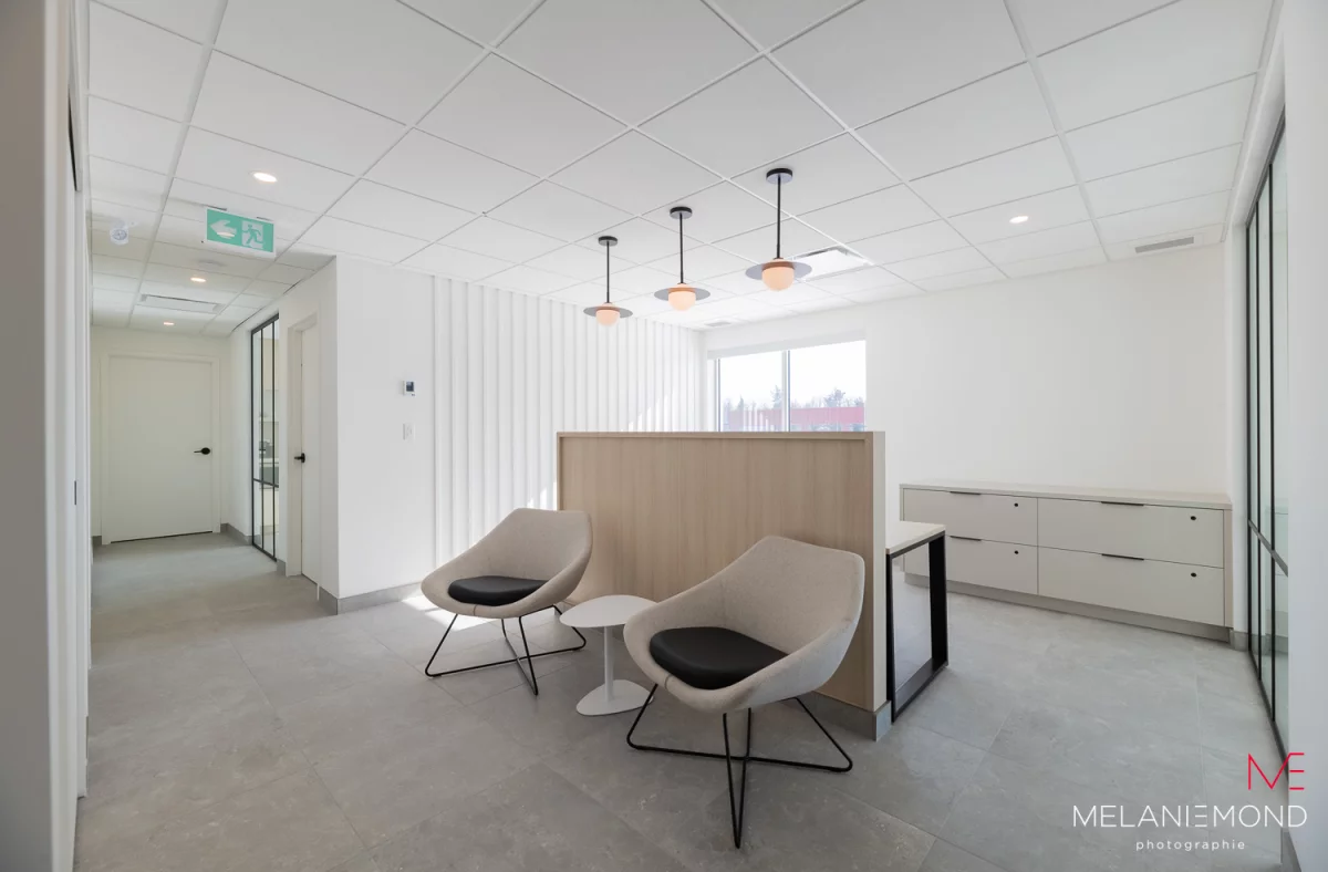Aire d'attente moderne avec fauteuils blancs et bureau en bois – aménagement intérieur Épandage YFL Joliette