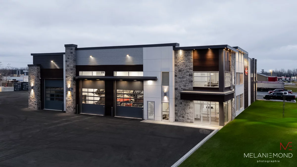 Vue d'angle du bâtiment avec section garage et bureaux vitrés – construction commerciale Épandage YFL Joliette par BGC