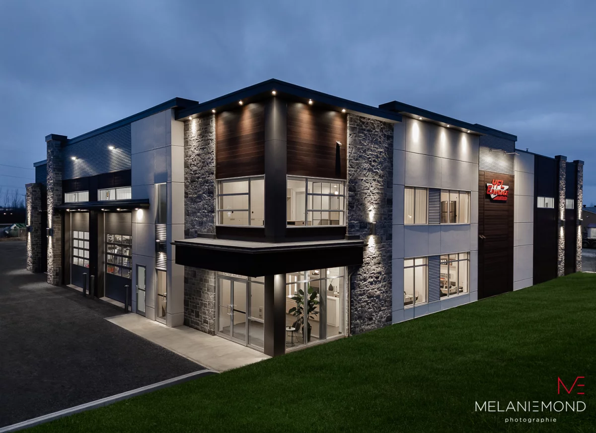 Bureaux Épandage YFL illuminés la nuit avec façade de pierre et grandes fenêtres – projet commercial Joliette par BGC