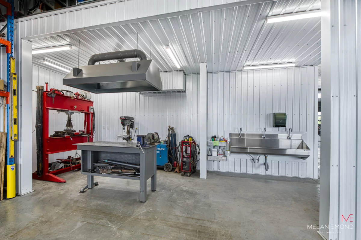 Atelier mécanique avec presse hydraulique rouge et établi – garage Épandage YFL Joliette par Gestion BGC