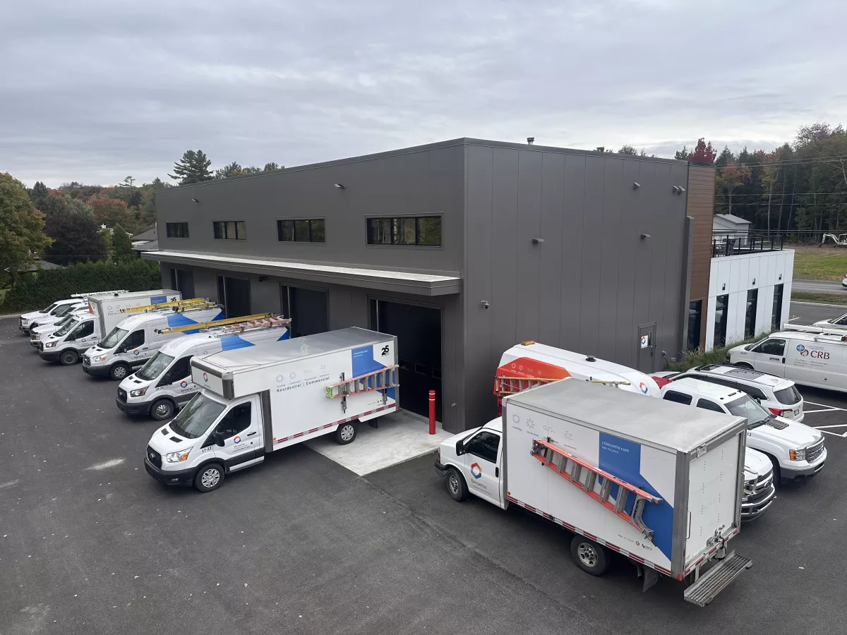 Cour de service avec flotte de véhicules Bessette devant le bâtiment gris – construction commerciale par BGC