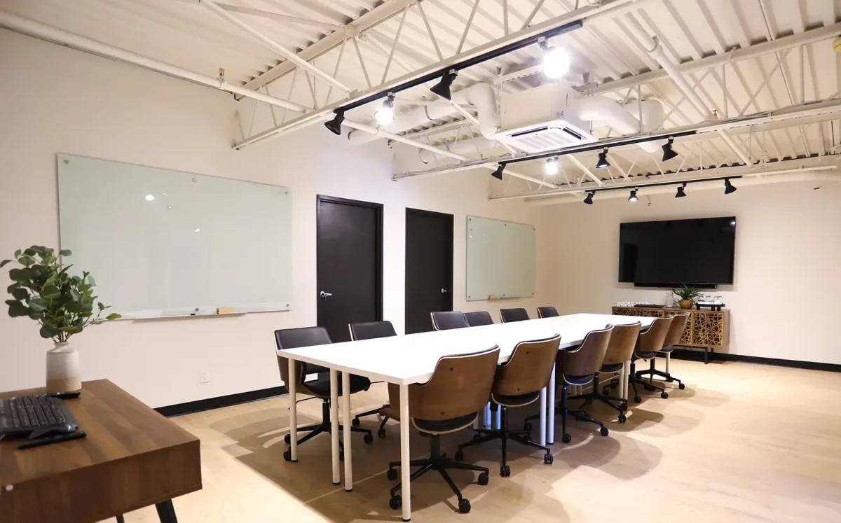Salle de conférence avec grande table blanche, tableaux de verre et plafond d'acier – bureaux commerciaux BGC