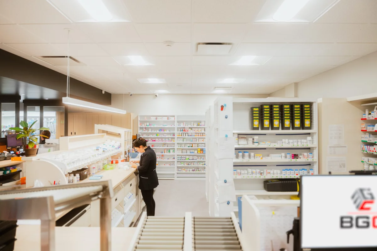 Arrière-pharmacie avec comptoirs de travail et rayonnages de médicaments – construction commerciale