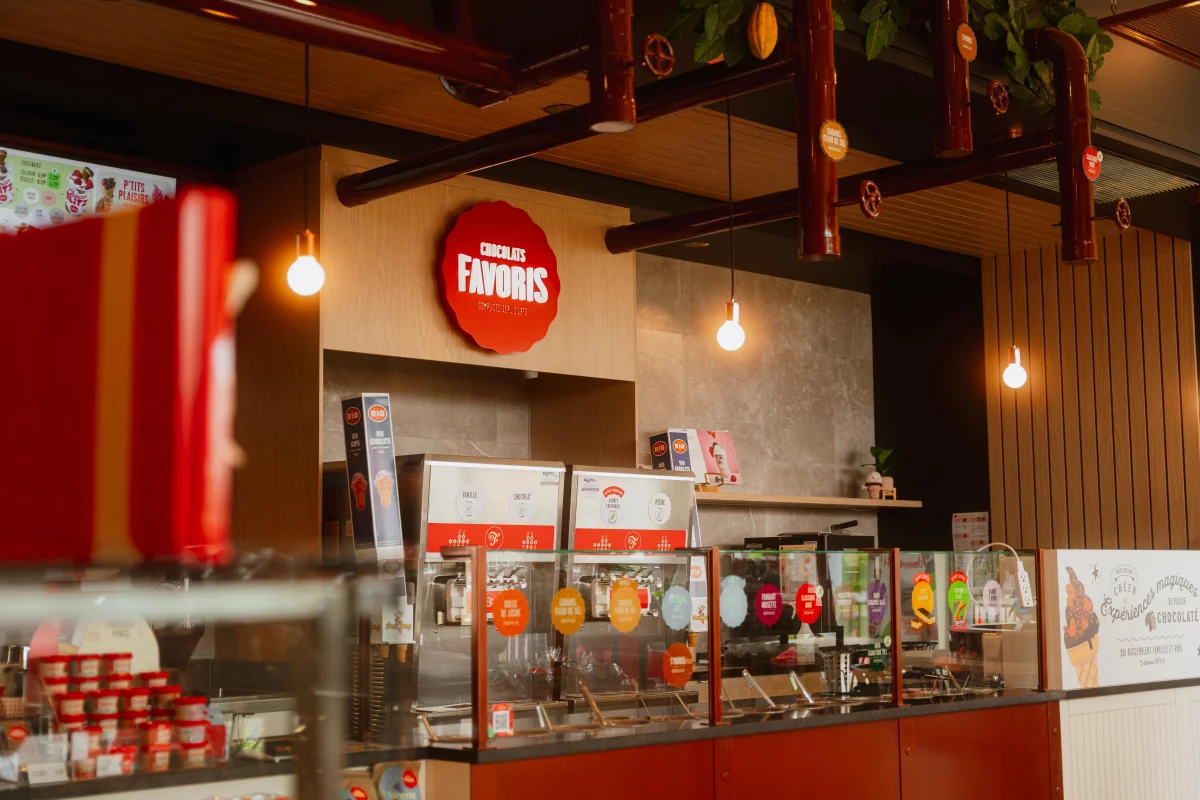 Comptoir de service avec logo Chocolats Favoris et tuyaux décoratifs – aménagement intérieur BGC