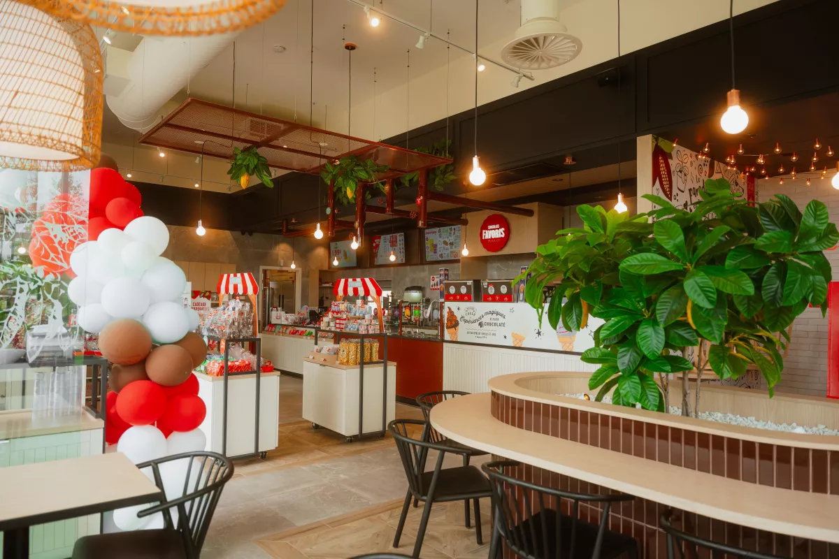 Aire de restauration avec banquettes courbes, plantes et éclairage suspendu