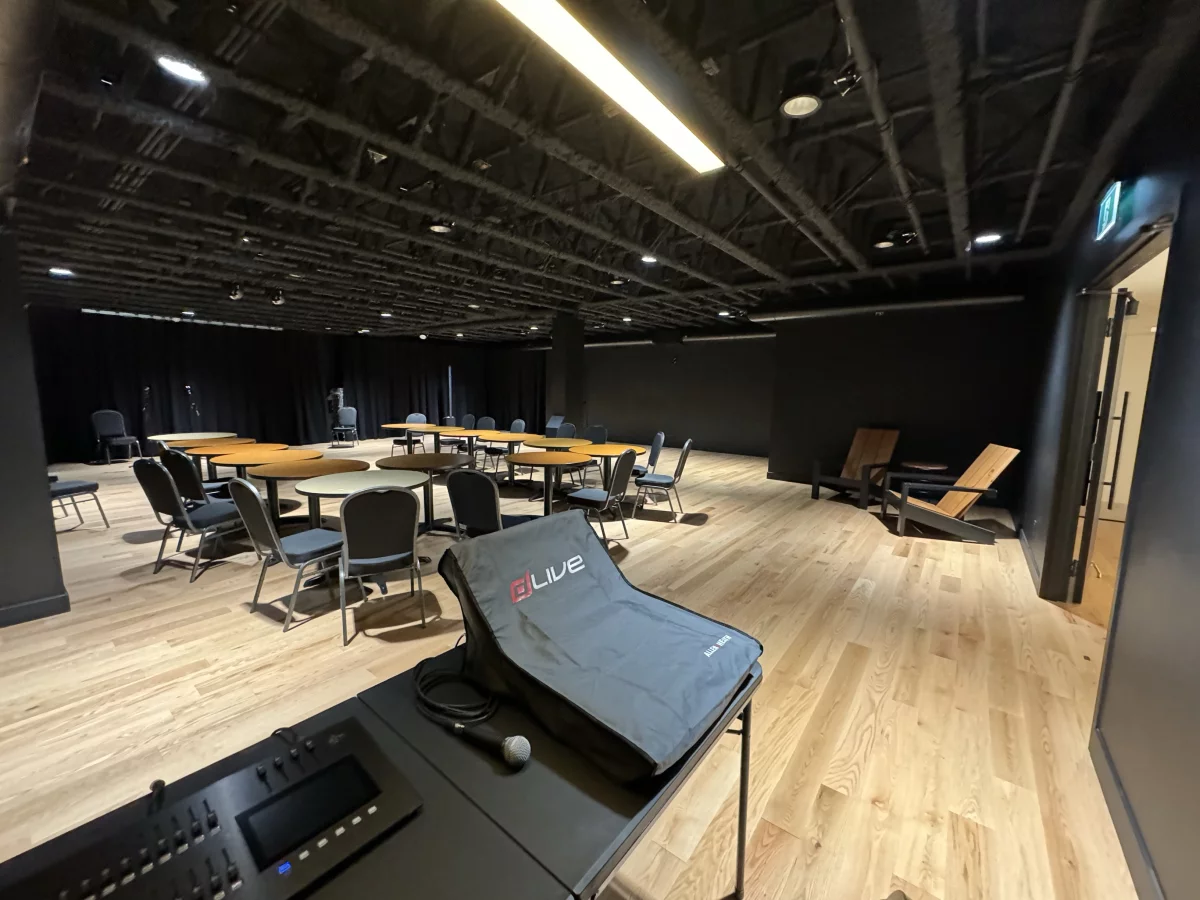 Salle multifonctionnelle avec console de son, tables rondes et plancher de bois