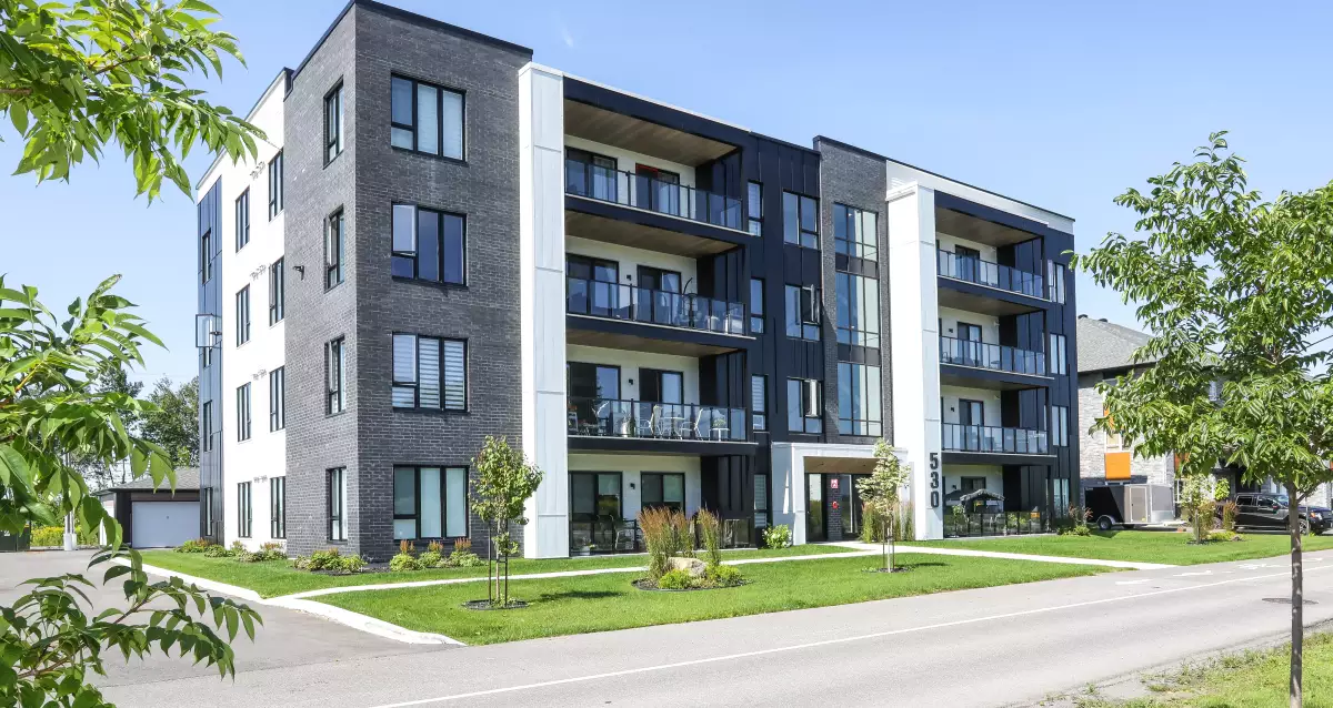 Façade multi-résidentielle avec balcons noirs et gazon – Les unités Munger