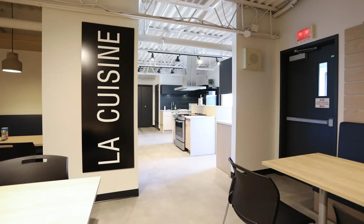 Cuisine des employés avec signalétique La Cuisine, comptoirs blancs et coin repas – aménagement commercial