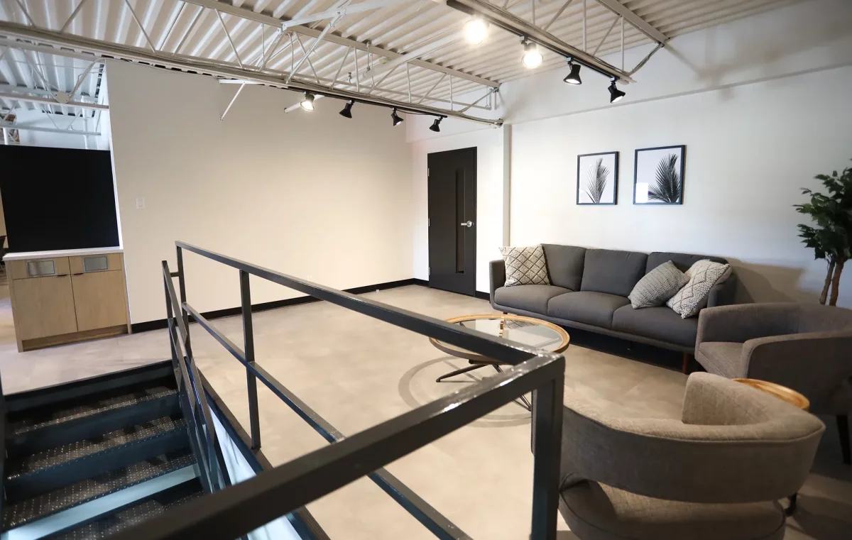Salon lounge avec mezzanine, garde-corps en acier noir et sofa gris – réaménagement intérieur Joliette