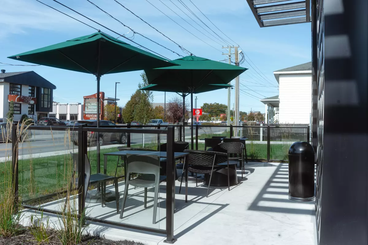 Terrasse du Starbucks avec tables sous parasols verts et graminées décoratives