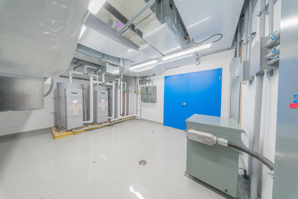 Salle technique avec panneaux électriques, conduits et plancher époxy