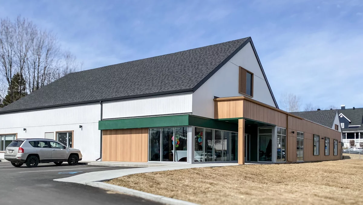 Entrée du CPE Moulin des bambins avec auvent vert et revêtement en bois – construction BGC