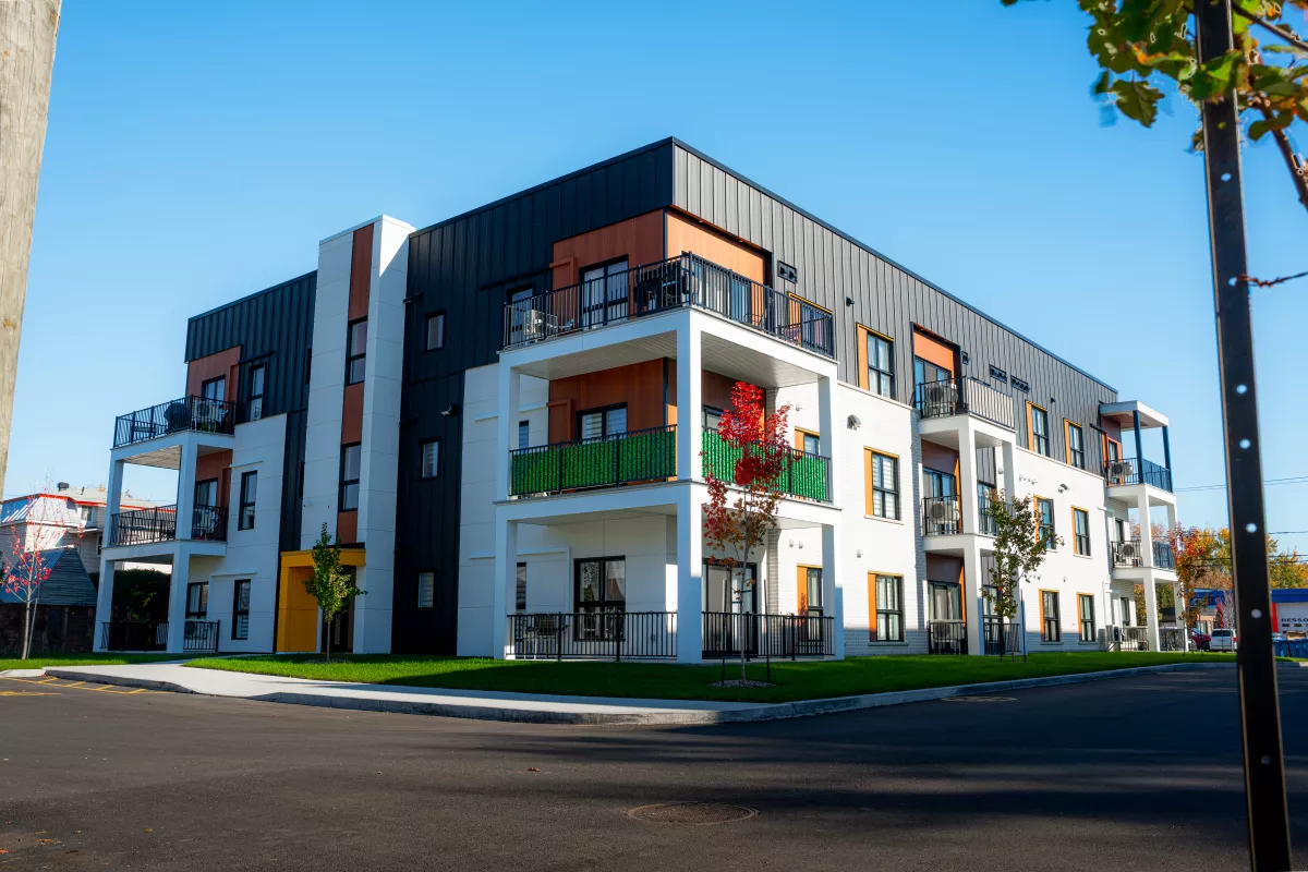 Immeuble multi-logements avec revêtement noir, balcons verts et entrée distinctive