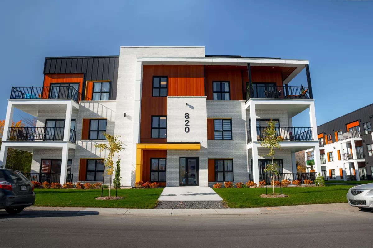 Façade du 800 avec entrée jaune, briques blanches et accents de bois – multi-résidentiel BGC