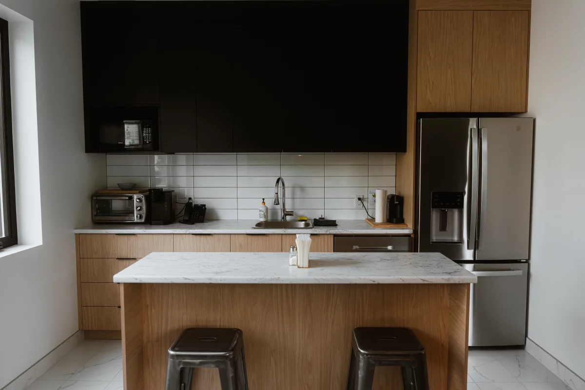 Cuisine d'employés avec armoires en chêne, îlot en marbre et dosseret blanc