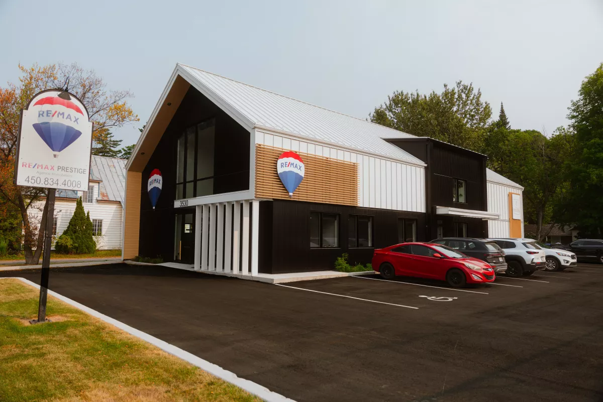 Façade RE/MAX Prestige – construction commerciale avec revêtement métallique noir et bois