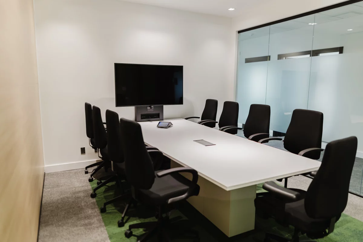 Salle de réunion avec écran mural, cloisons vitrées givrées et corridor – Desjardins par BGC Lanaudière