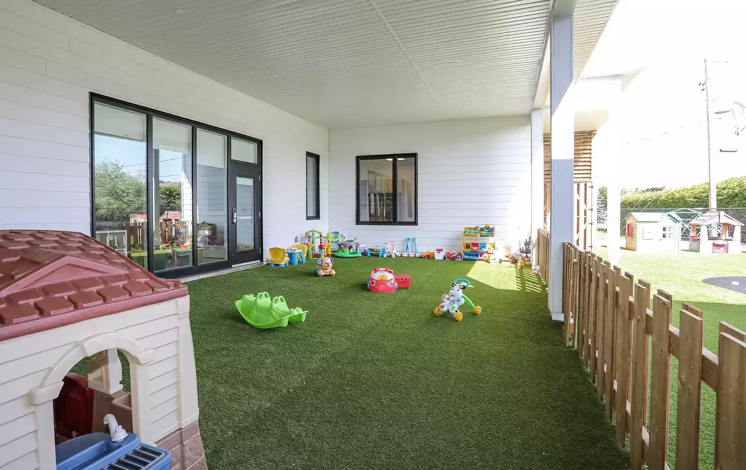 Cour extérieure avec gazon synthétique, maisonnette et jouets – aire de jeux Garderie Maxi-Mousse Lanaudière