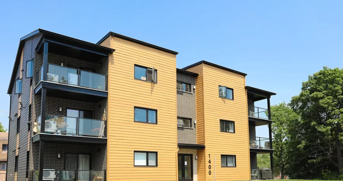 Façade multi-logements avec accents de briques noires et revêtement brun doré – projet résidentiel Gestion BGC