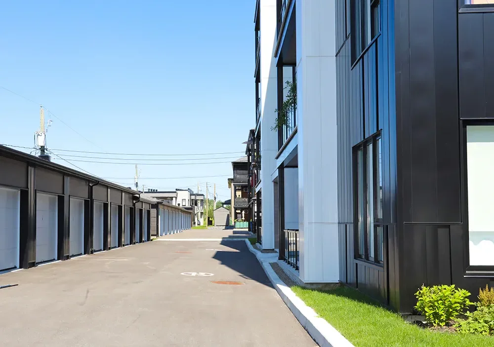 Ruelle arrière avec garages privés et façade moderne en revêtement noir – 16 unités Munger St-Charles-Borromée